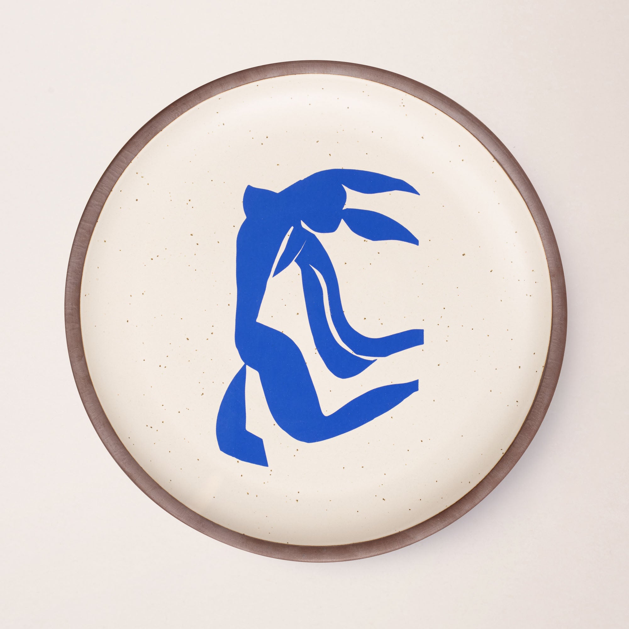 A large serving platter in a warm off-white color with unglazed rim with a blue decal of the artwork, La Chevelure, from Henri Matisse.