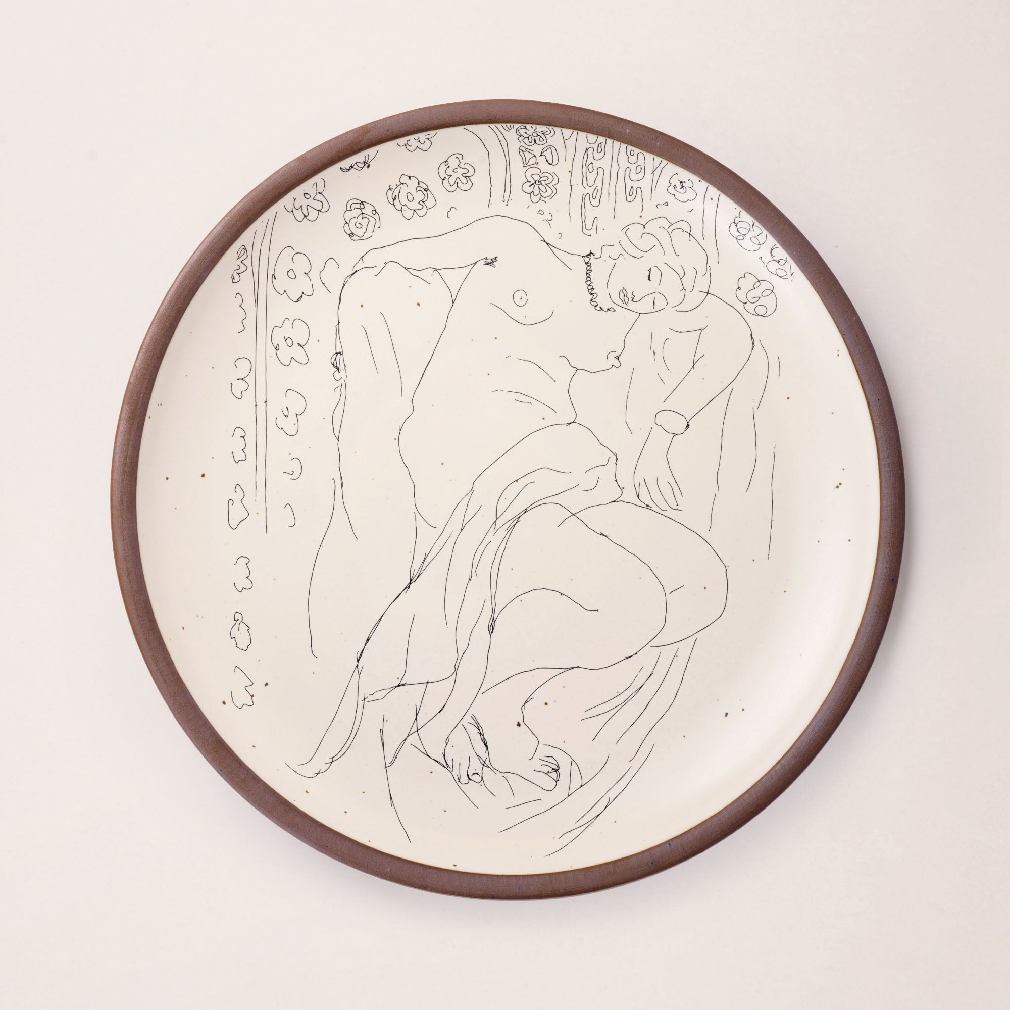 A large serving platter in a warm off-white color with unglazed rim with a black decal of the artwork, Figure endormie sur fond moucharabieh, from Henri Matisse.
