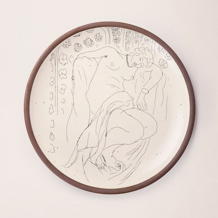 A large serving platter in a warm off-white color with unglazed rim with a black decal of the artwork, Figure endormie sur fond moucharabieh, from Henri Matisse.