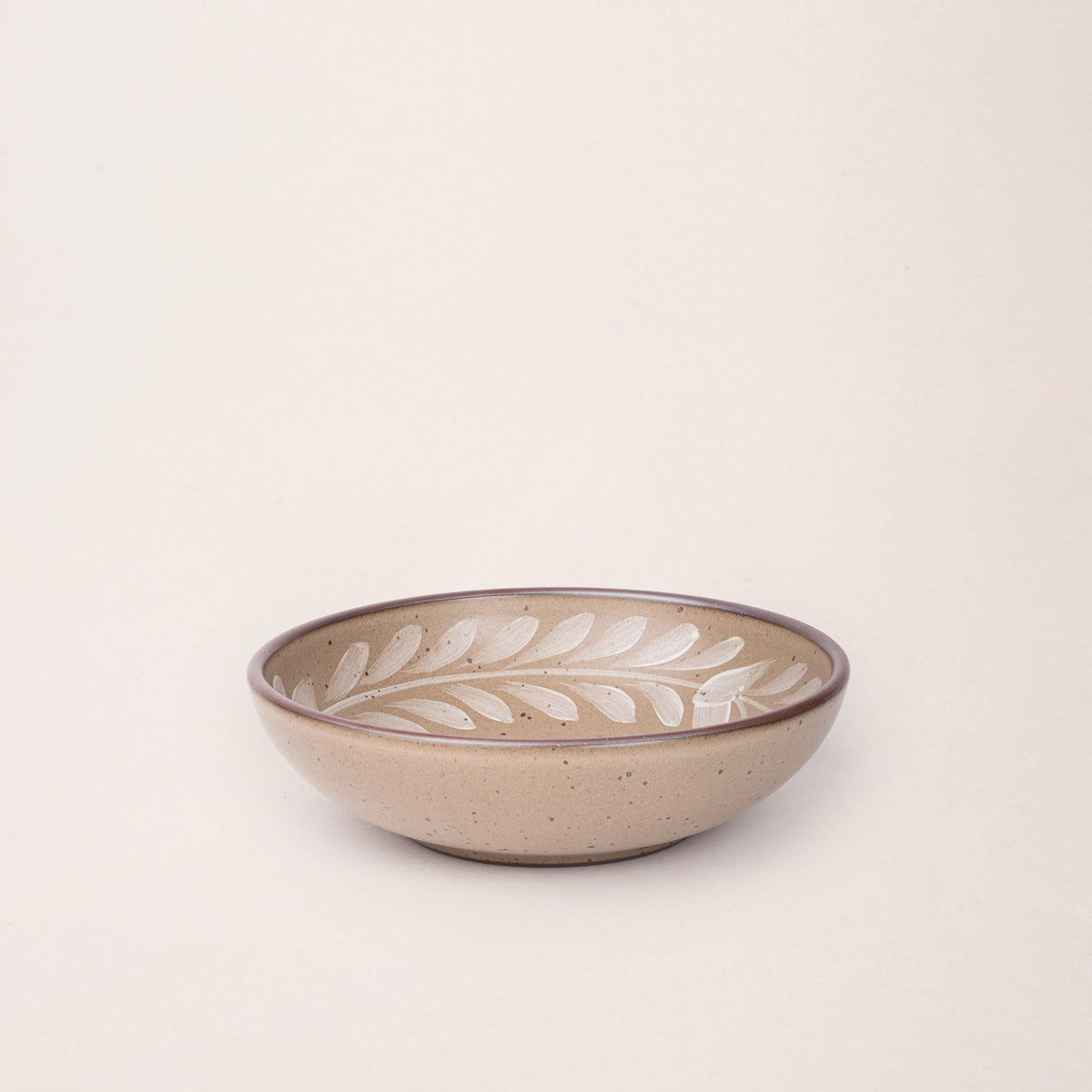 Medium ceramic shallow bowl with a hand-painted white leaf border on a pale warm brown interior and exterior with an exposed clay rim.