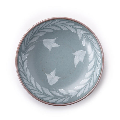 Overhead view of Large ceramic shallow bowl with a hand-painted white leaf border on a blue-grey interior and exterior with an exposed clay rim.