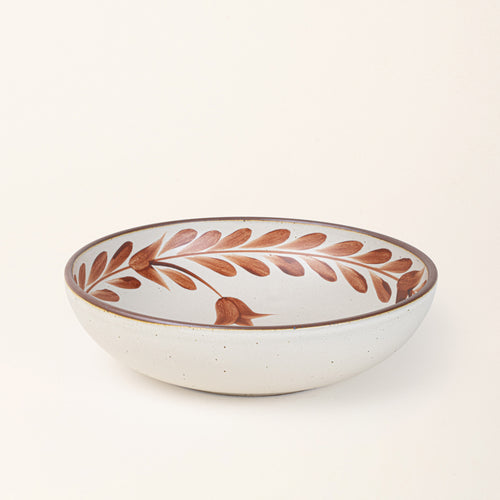 Large ceramic shallow bowl with a hand-painted cool terracotta leaf border on a cream interior and exterior with an exposed clay rim.