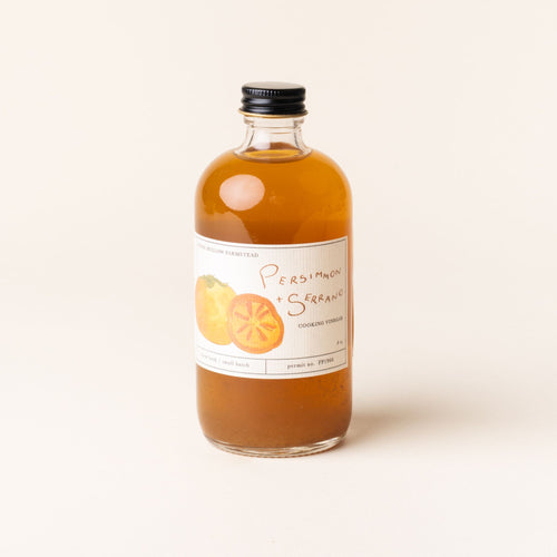 Bottle of Persimmon + Serrano cooking vinegar, featuring hand-drawn persimmon illustrations on the label.
