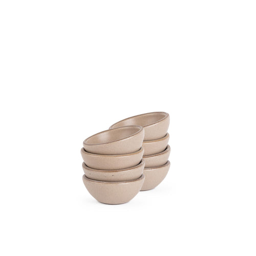 A stack of 8 tiny rounded ceramic bowls in a warm pale brown color featuring iron speckles and an unglazed rim