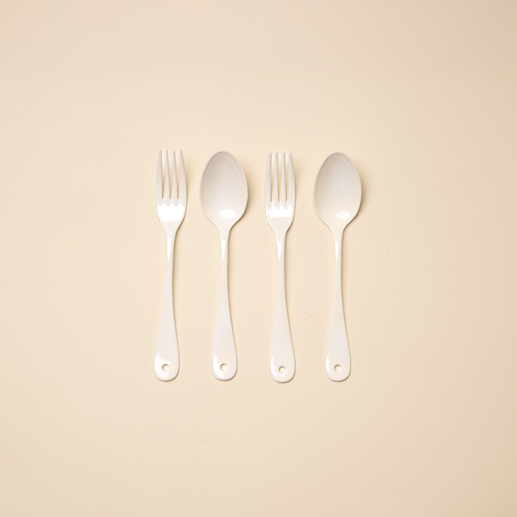 2 dinner forks and 2 dinner spoons made of white enamel lined in a row.
