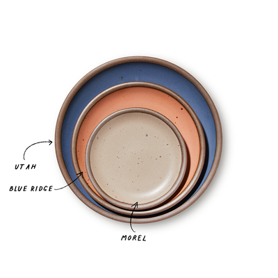 A stack of 3 plates in Dinner, Side, and Cake sizes in a navy, peach, and pale warm brown colors.