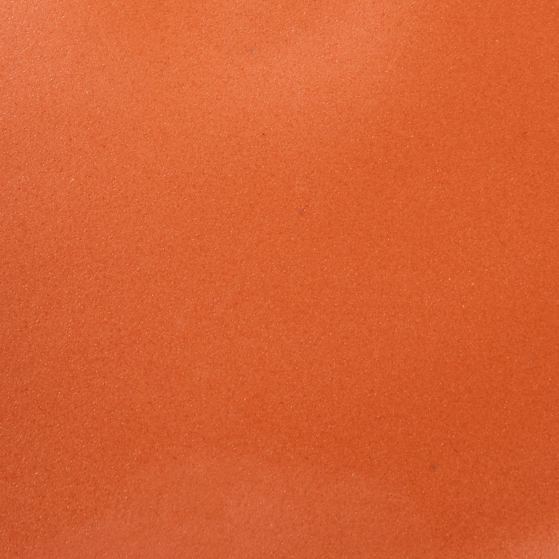 A closeup of a ceramic plate in a bold orange color
