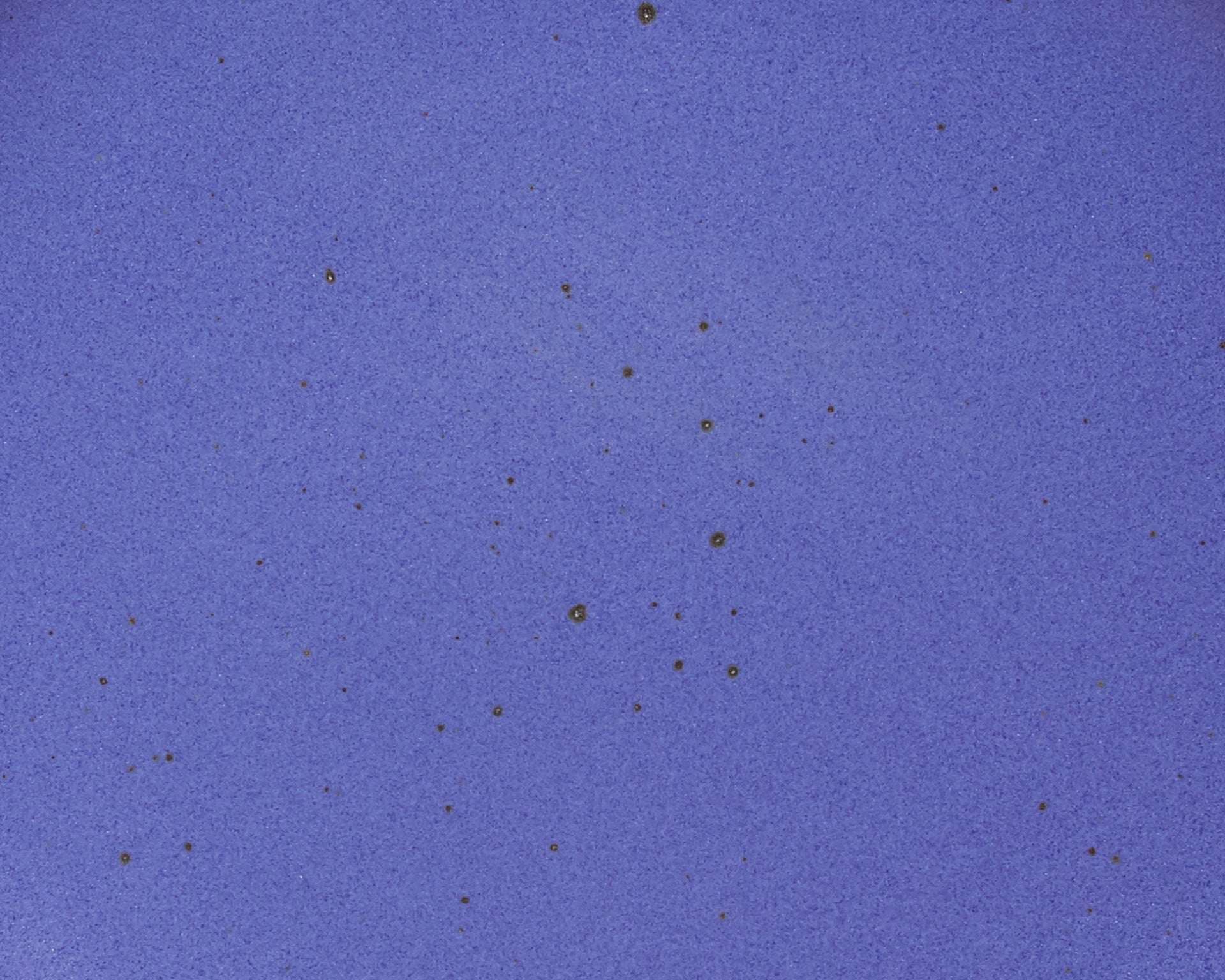 A closeup of a ceramic plate in a true cool blue color featuring iron speckles