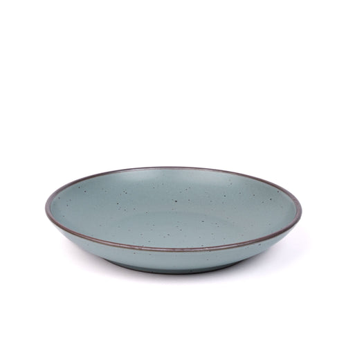 A large ceramic plate with a curved bowl edge in a blue-grey color featuring iron speckles and an unglazed rim.