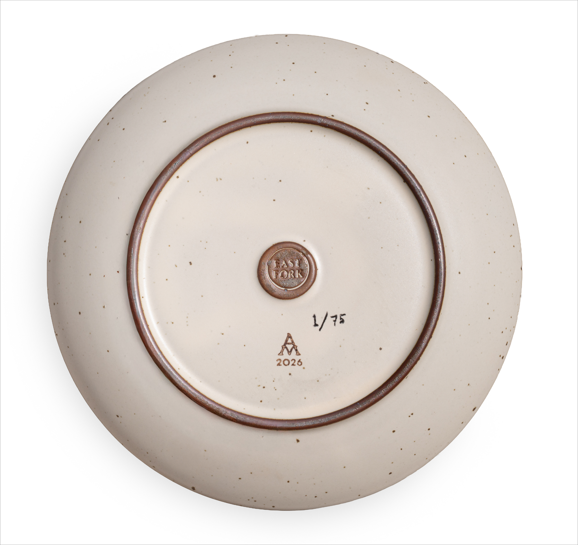 The back of a ceramic plate with iron spots in an off-white color, with a EAST FORK stamp, and an artist signature and edition of 1/75. 