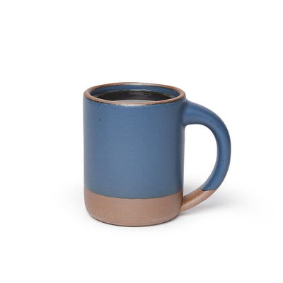 A big sized ceramic mug filled with coffee with handle in a toned-down navy glaze featuring iron speckles and unglazed rim and bottom base.