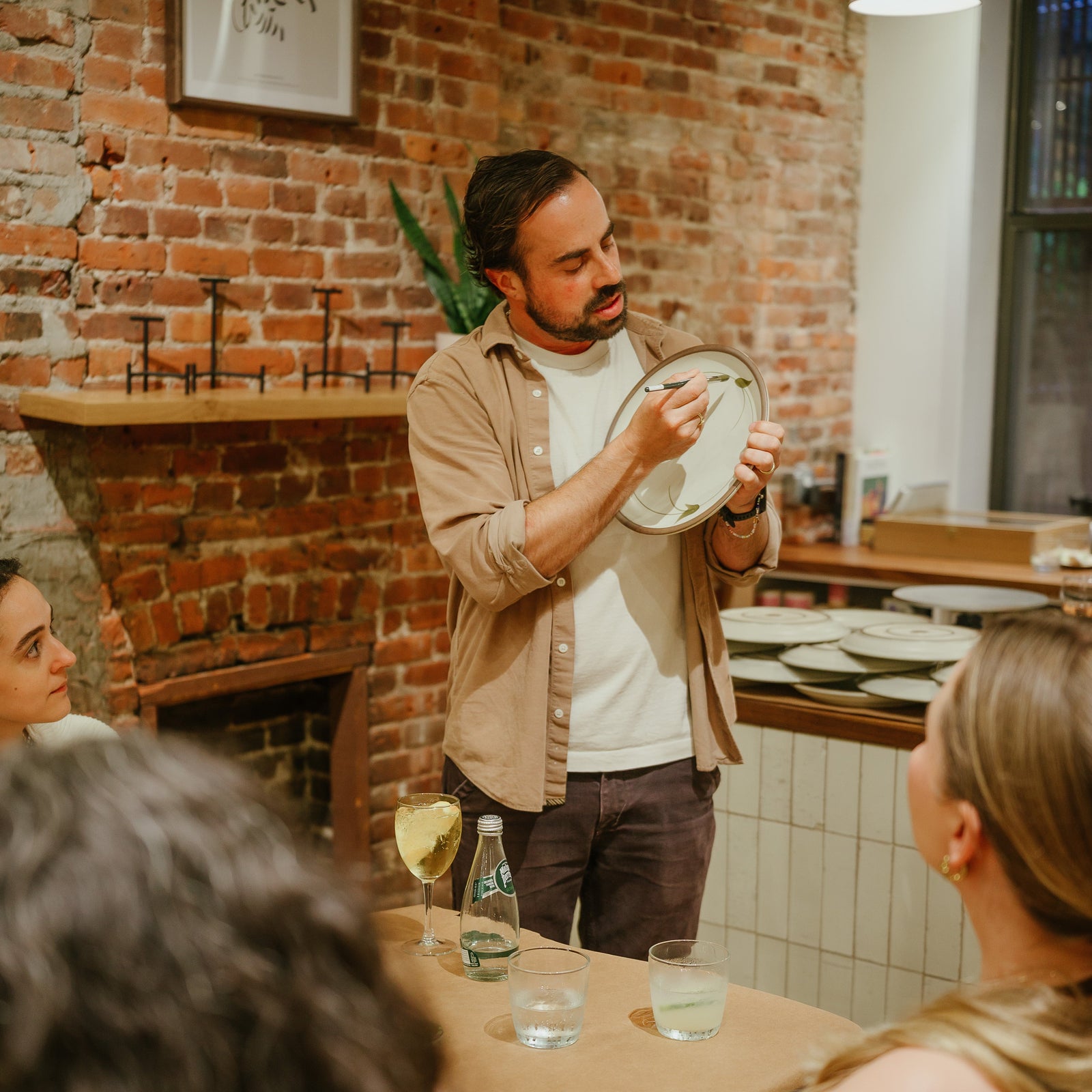Alex teaching a painting workshop holding a ceramic plate and paintbrush