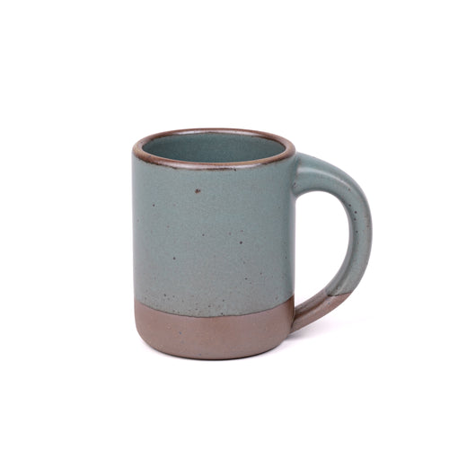 A big sized ceramic mug with handle in a blue-grey color featuring iron speckles and unglazed rim and bottom base.
