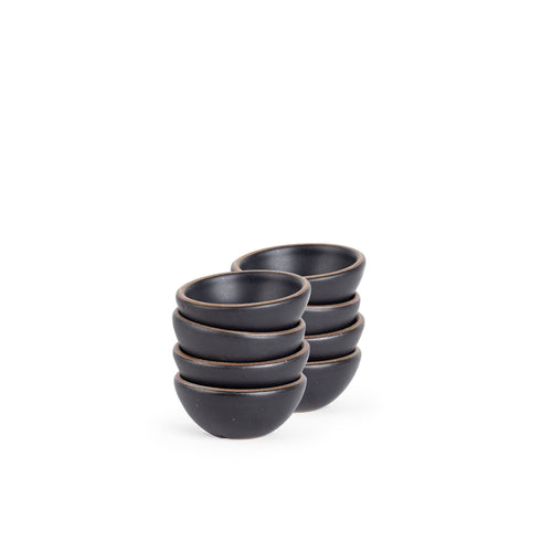A stack of 8 tiny rounded ceramic bowls in a graphite black color featuring iron speckles and an unglazed rim