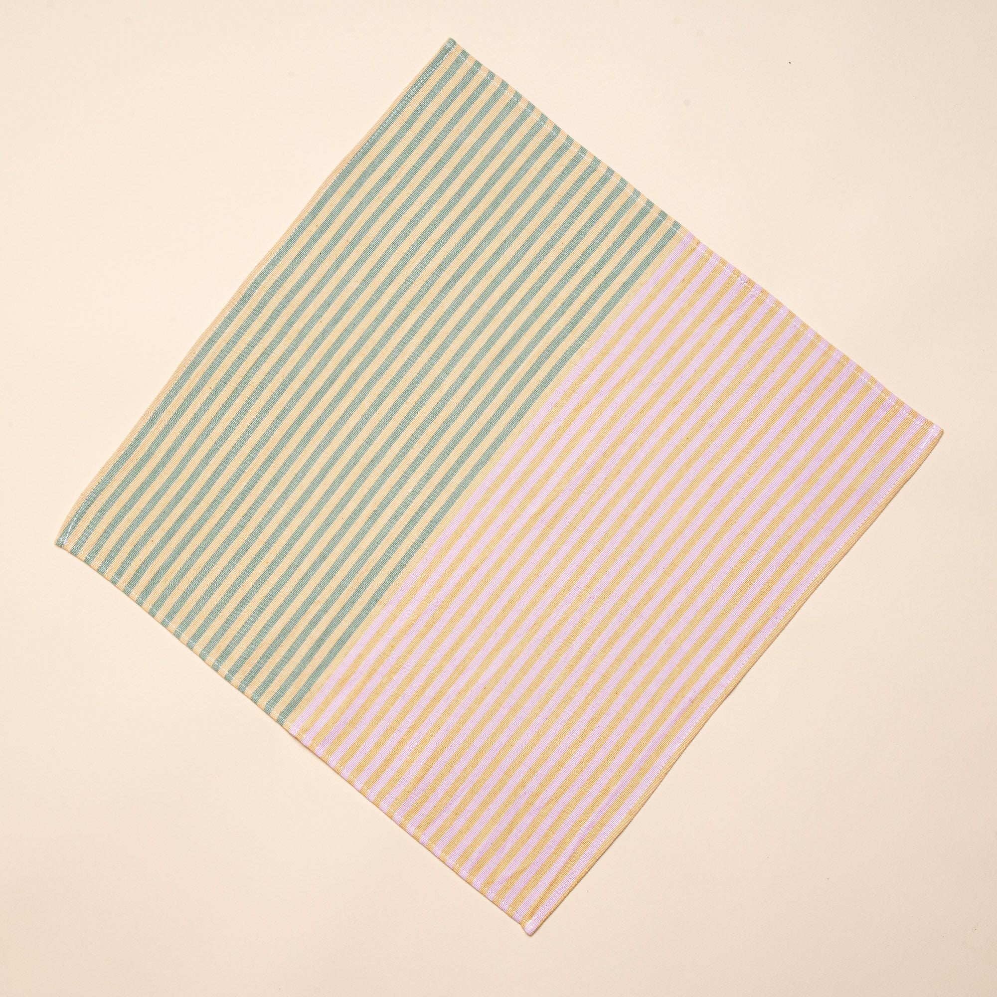 A square napkin that is half striped green and peach, the other half is striped pink and peach.