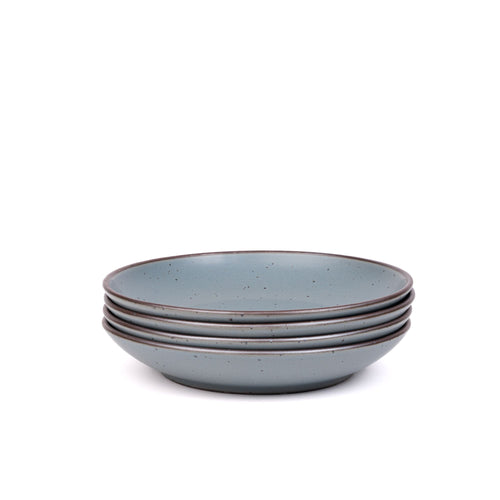 A stack of 4 large ceramic plates with a curved bowl edge in a blue-grey color featuring iron speckles and an unglazed rim.