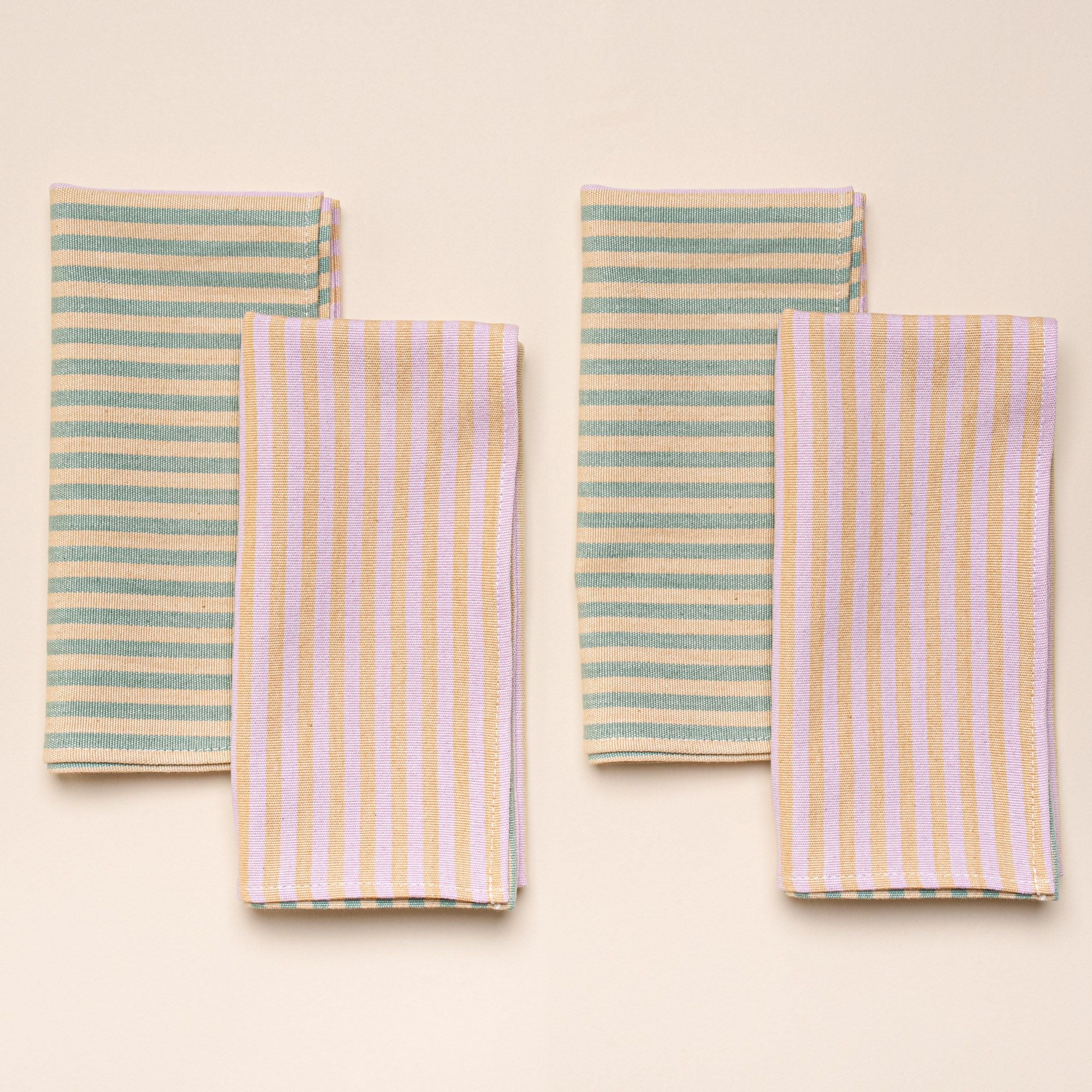 4 folded napkins featuring color blocks of striped peach and pink, and striped peach and green.