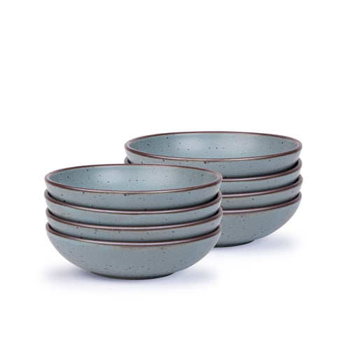 A stack of 8 dinner-sized shallow ceramic bowls in a blue-grey color featuring iron speckles and an unglazed rim