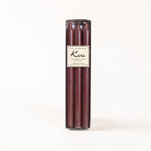 A narrow box of brown taper candles with a cream label.