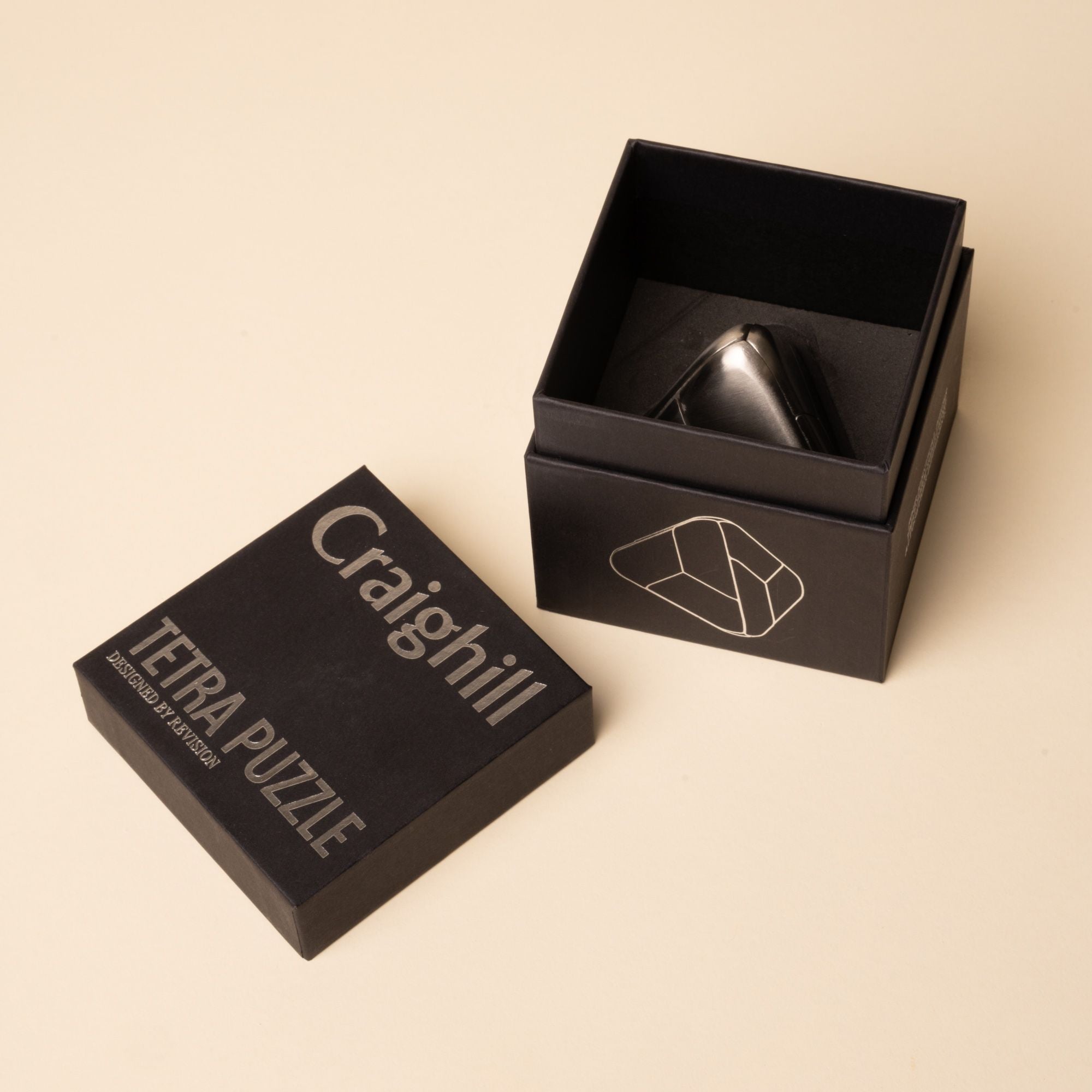 Open black box with "Craighill Tetra Puzzle" printed on the lid, revealing a triangular metal puzzle inside.