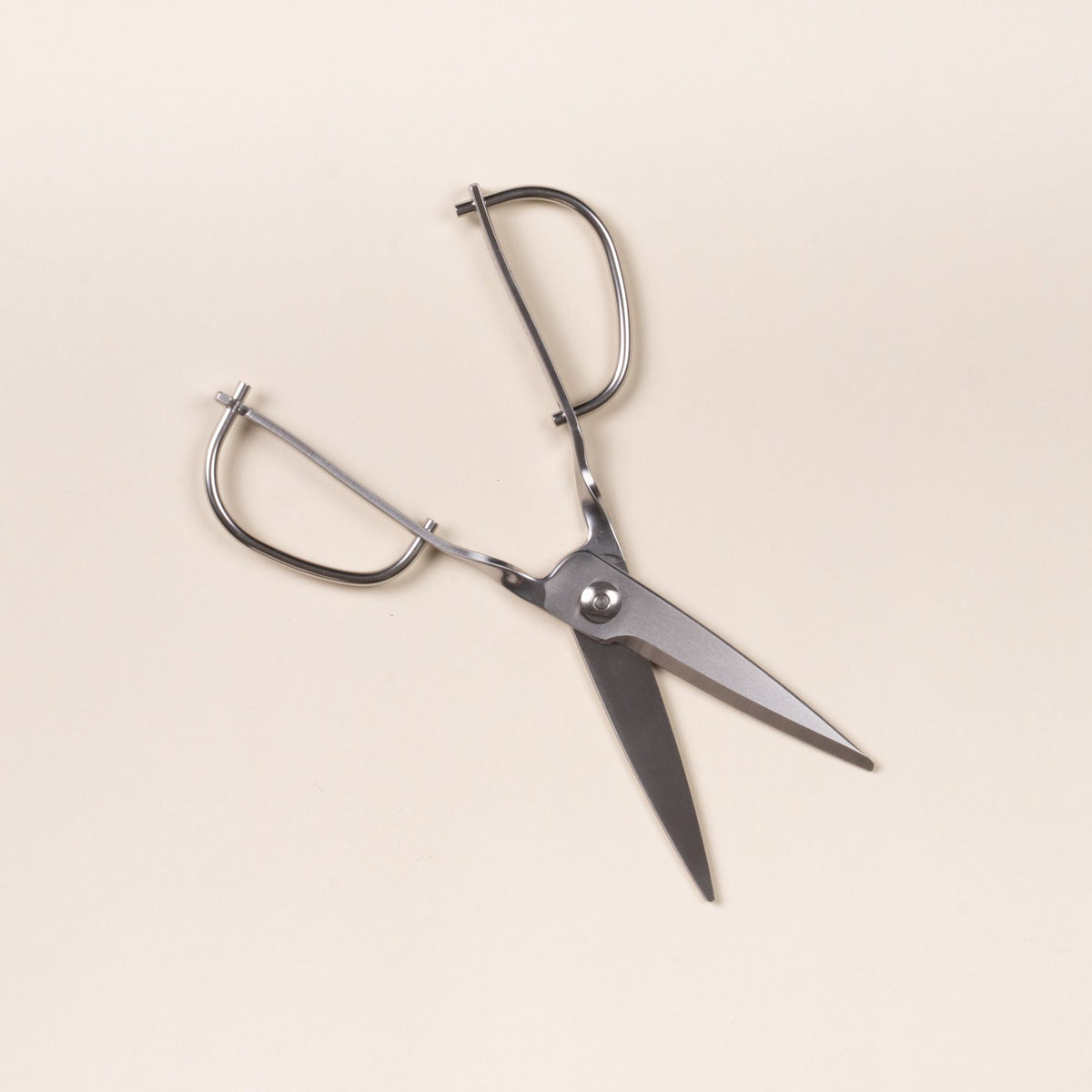Open stainless steel kitchen scissors with a looped handle, on a light neutral background.