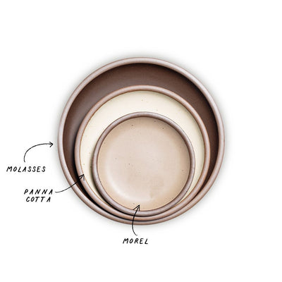 A stack of 3 plates in Dinner, Side, and Cake sizes in a dark brown, warm off-white, and warm beige colors.