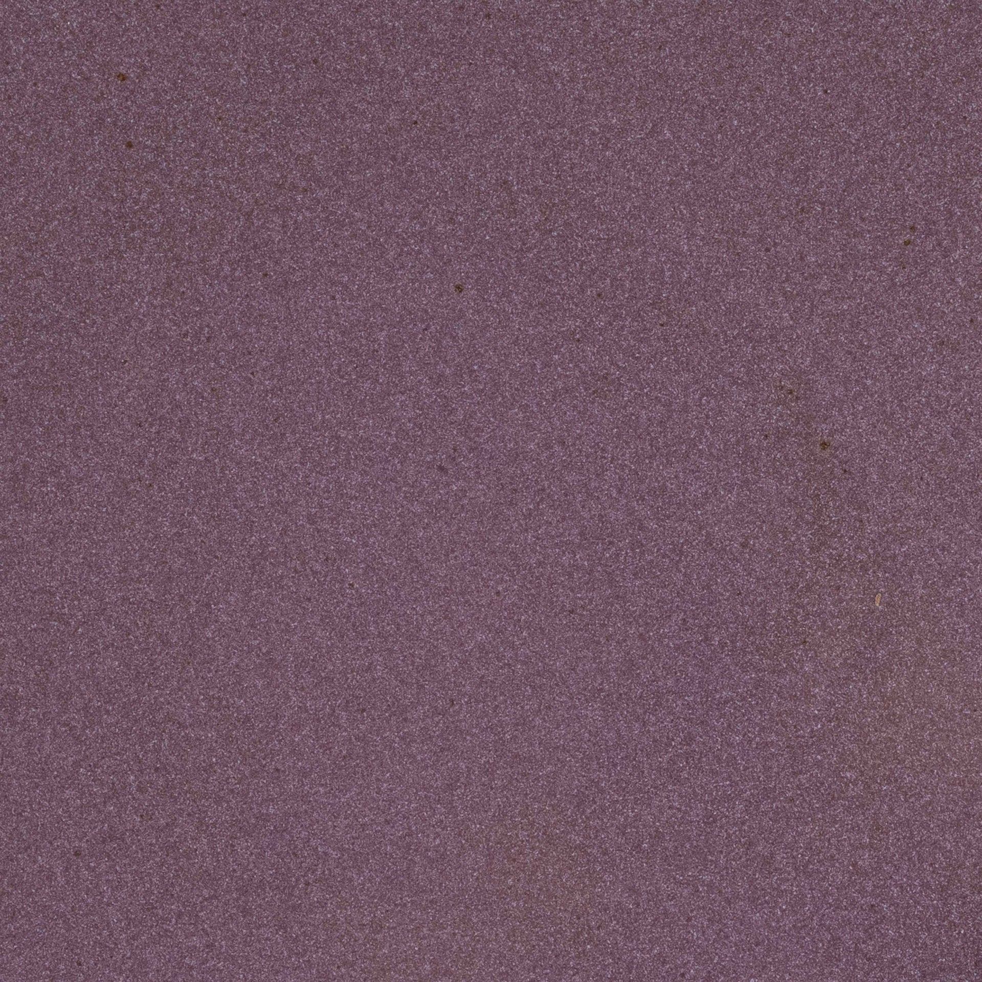 A closeup of a ceramic plate in a purple color with a soft, glowing sheen and iron speckles throughout