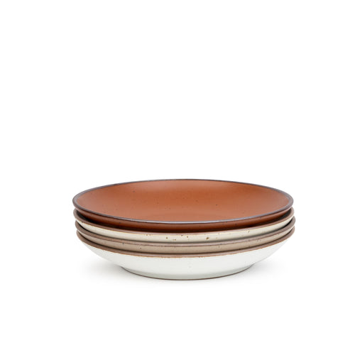 A stack of 4 large ceramic plates with a curved bowl edge in a cool terracotta, warm off-white, cool white, and warm pale brown colors featuring iron speckles and an unglazed rim.