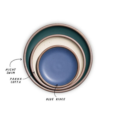 A stack of 3 plates in Dinner, Side, and Cake sizes in a dark teal, warm off-white, and navy colors.