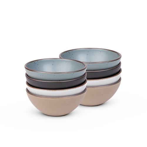 A stack of 8 medium sized rounded ceramic bowls in a blue-grey, graphite black, cool white, and warm pale brown colors featuring iron speckles and an unglazed rim