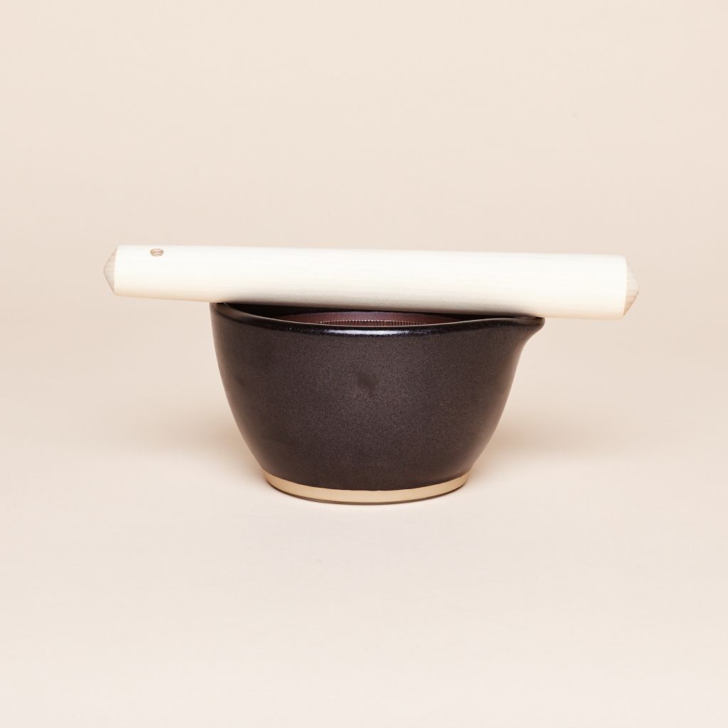 Black mortar with white pestle balanced across its top edge