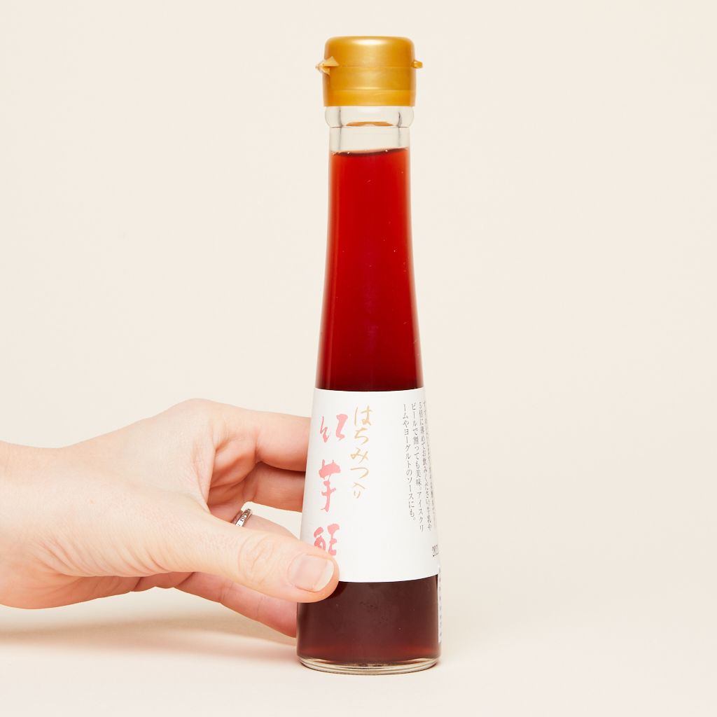 A hand holds a bottle of sweet potato vinegar