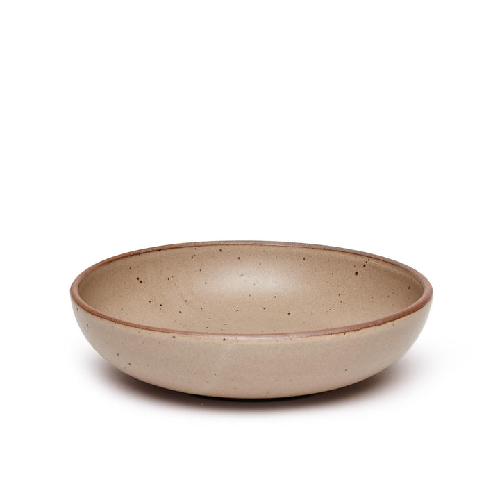 A large shallow serving ceramic bowl in a pale warm brown color featuring iron speckles and an unglazed rim.