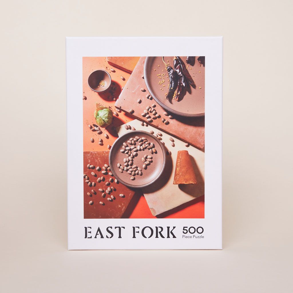 Front of the box that contains a 500-piece jigsaw puzzle showing pottery glazed in Pinto, pinto beans, square tiles and a brown sugar cone