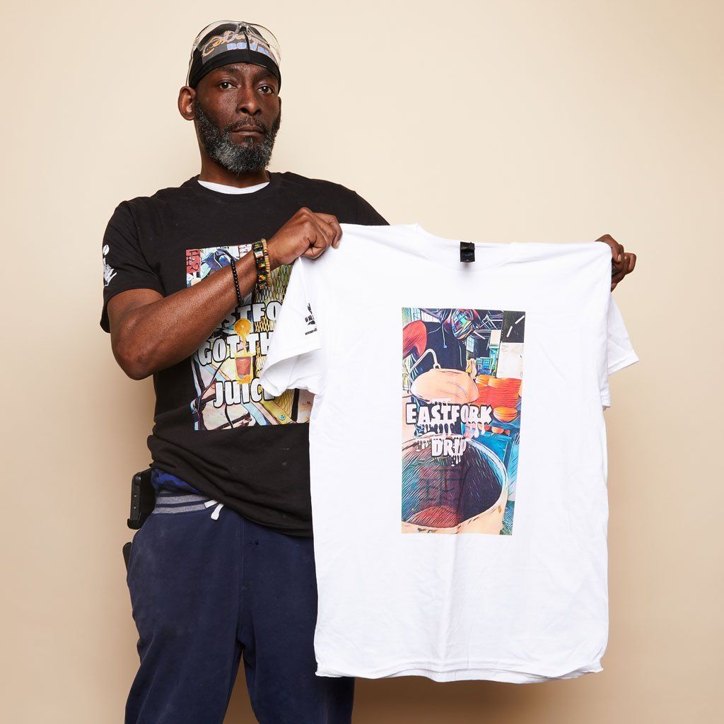 A person in a black Drip Life tee holds a white Drip Life tee.
