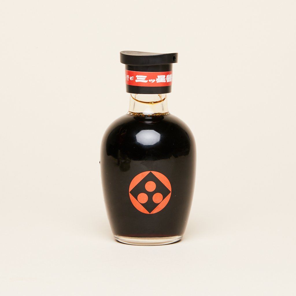 A bottle of soy sauce, filled with a black cap