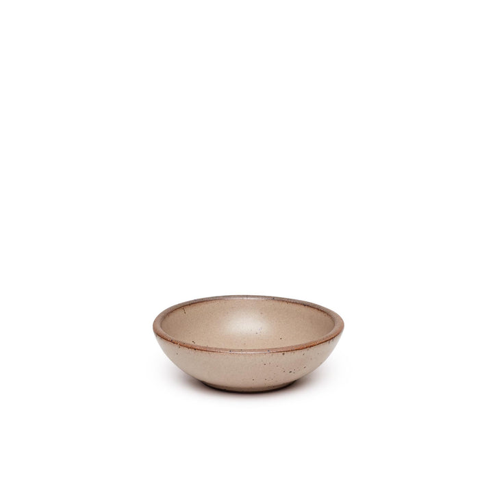 A small shallow ceramic bowl in a pale warm brown color featuring iron speckles and an unglazed rim