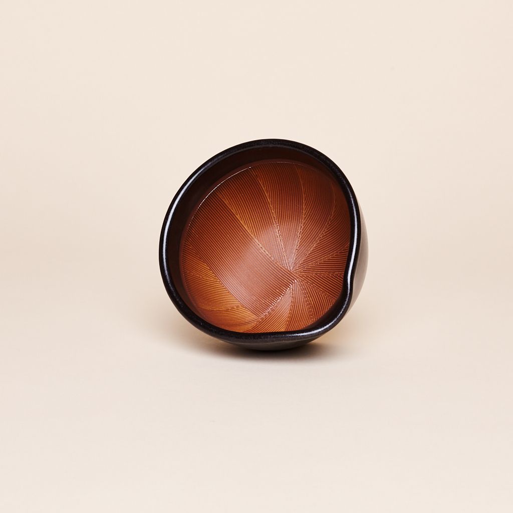 Mortar positioned to show the inside, which is reddish brown and black rim that has a spout for pouring.