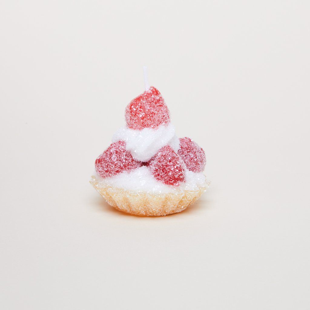 A candle that has the size, shape and color of a pastry shell with icing and sugar-sprinkled red berries.