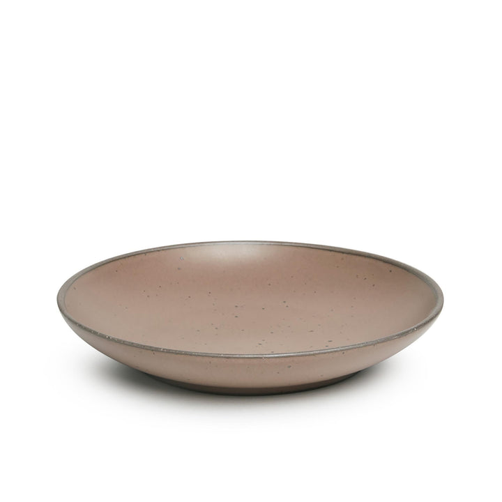 A large ceramic plate with a curved bowl edge in a pale warm brown color featuring iron speckles and an unglazed rim.