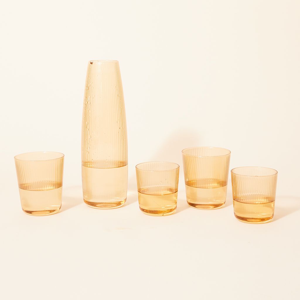 Four pale yellow drinking glasses and matching pitcher with a spout at the rim