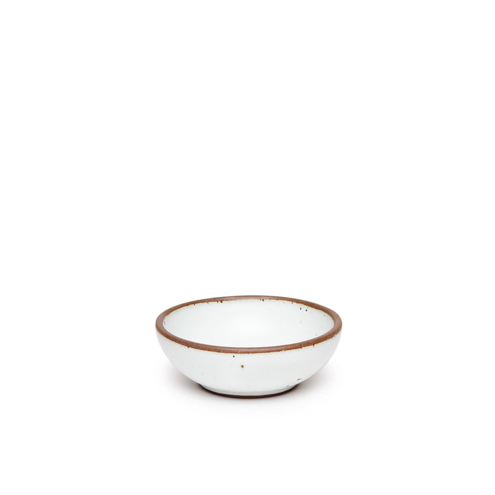 A small shallow ceramic bowl in a cool white color featuring iron speckles and an unglazed rim
